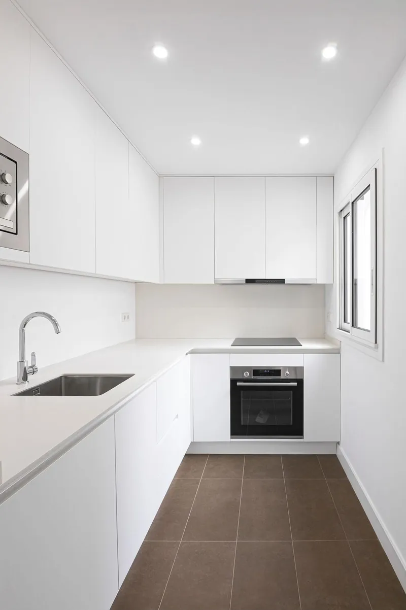 Cocina reformada en blanco con suelo porcelánico oscuro
